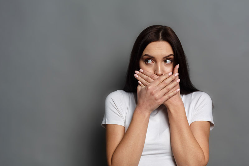 Dental Patient Covering Her Missing Teeth In Her Mouth